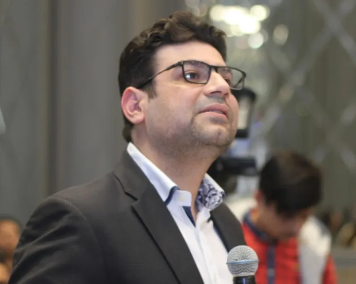 A man in a suit and tie holding a microphone.