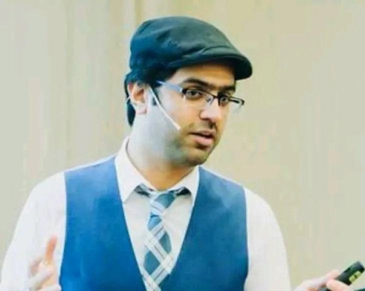 A man wearing a blue vest and tie holding a cell phone.